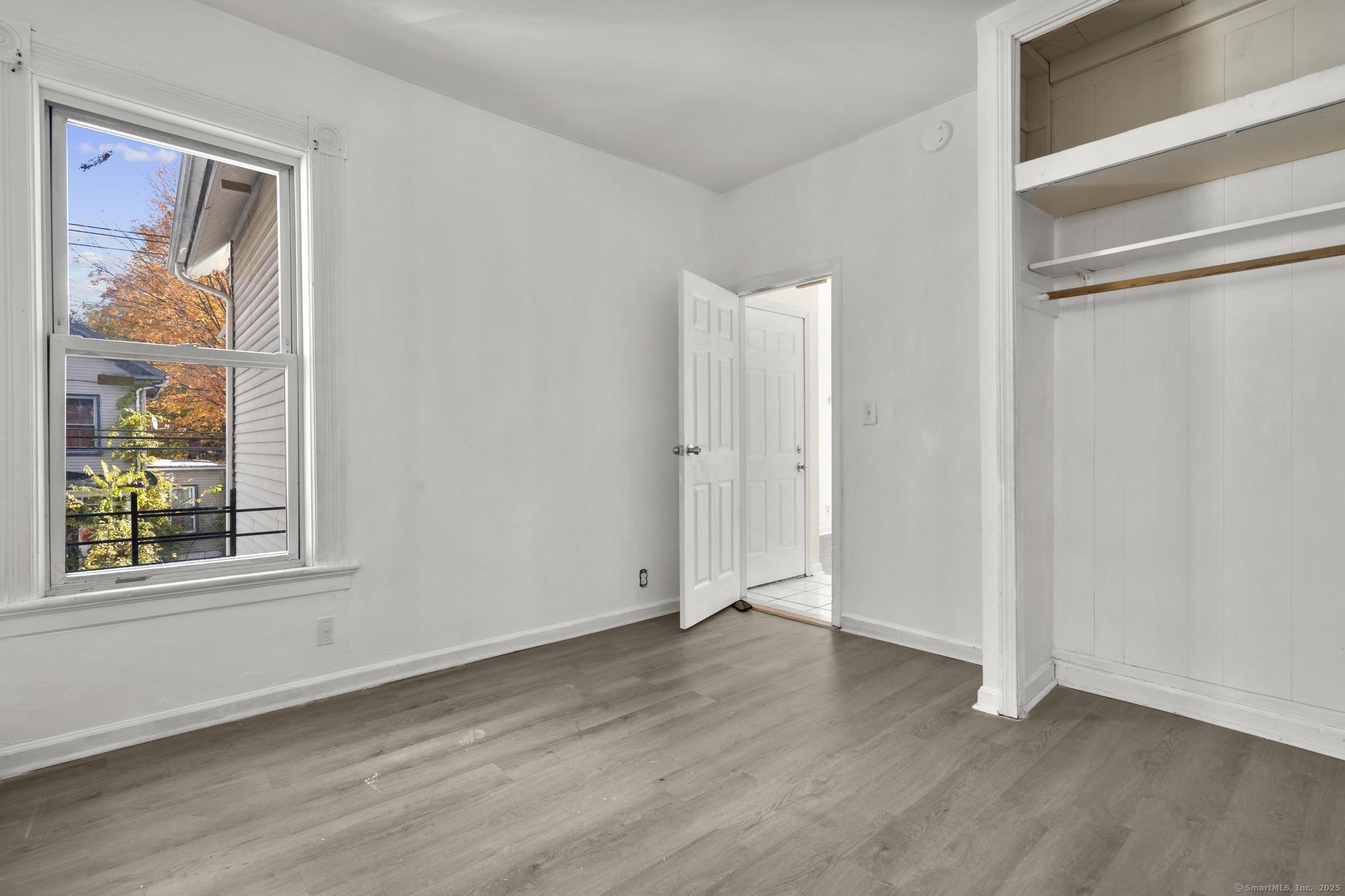 141 Crown Street, Unit 2 Meriden, CT 06450 - Photo 5 of 9 an empty room with wooden floor and windows