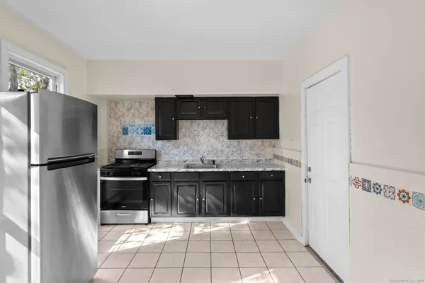 a kitchen with granite countertop a refrigerator and a stove top oven