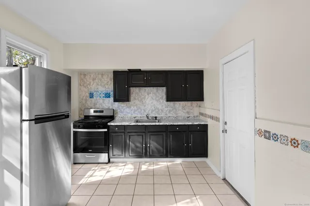 a kitchen with granite countertop a refrigerator and a stove top oven