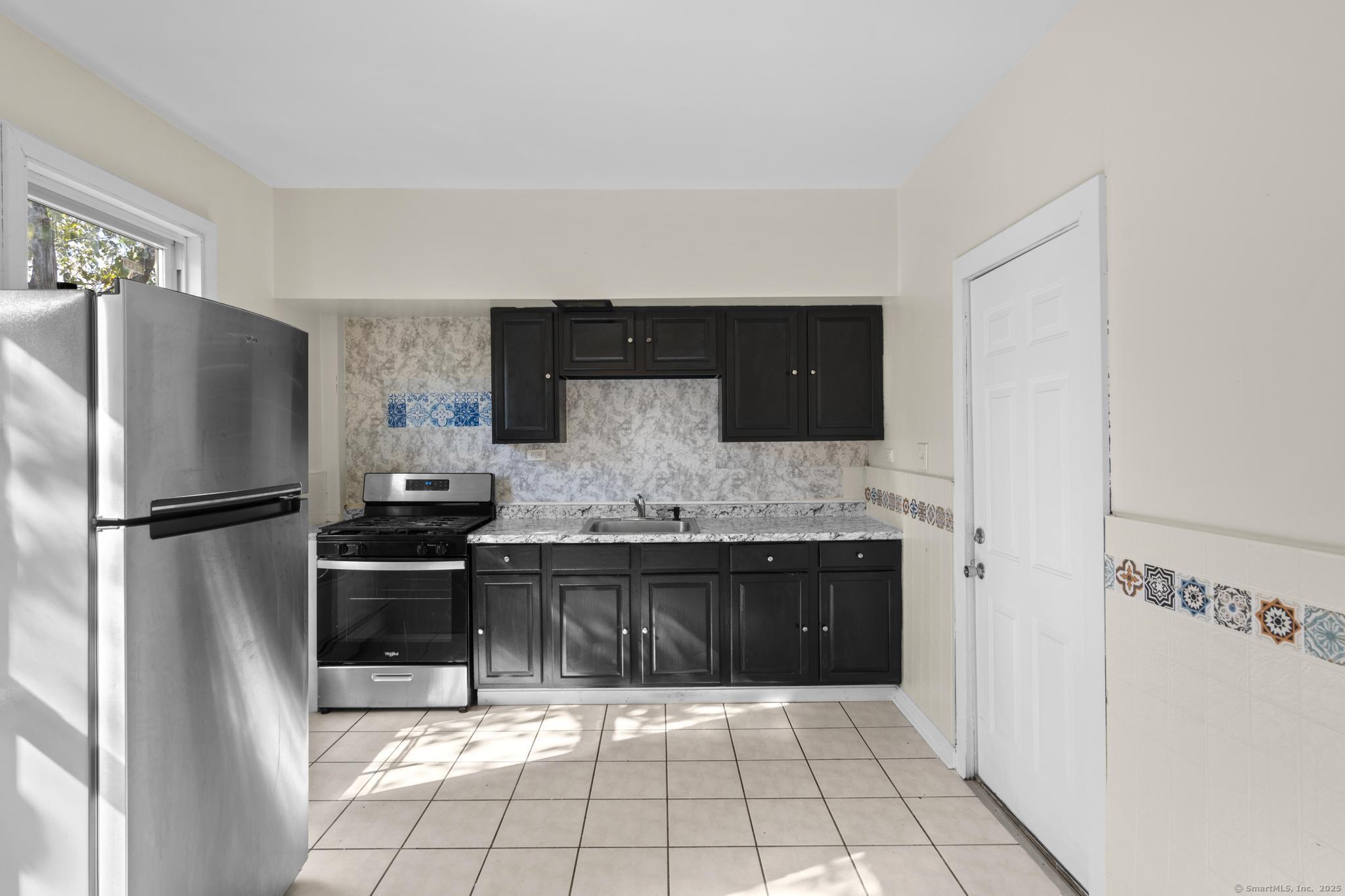 141 Crown Street, Unit 2 Meriden, CT 06450 - Photo 9 of 9 a kitchen with granite countertop a refrigerator and a stove top oven