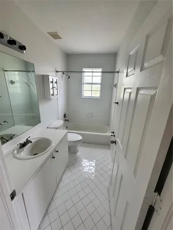 a bathroom with a granite countertop sink a mirror a tub and shower