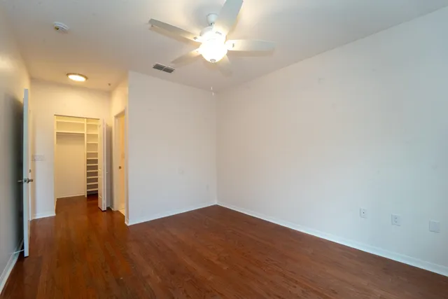 an empty room with wooden floor and a ceiling fan