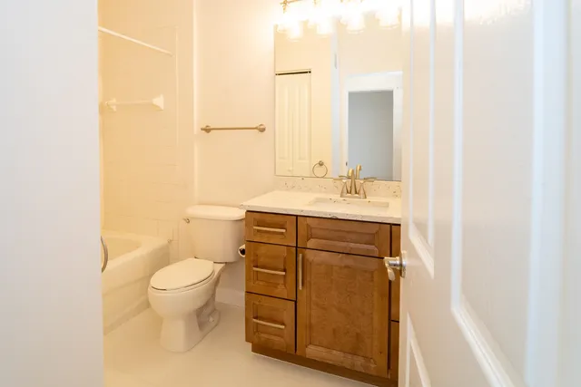 a bathroom with a granite countertop sink toilet and mirror