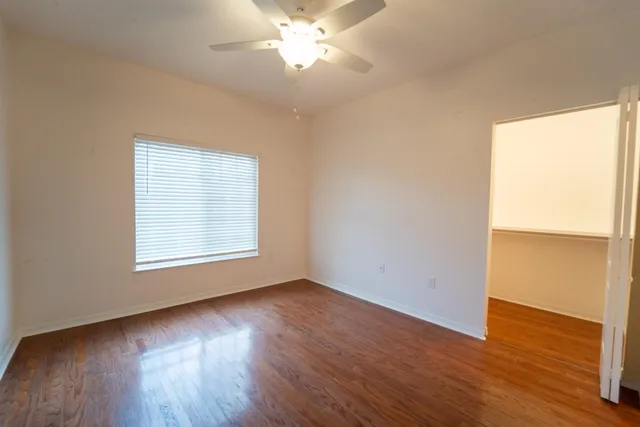 a view of an empty room with wooden floor and a window