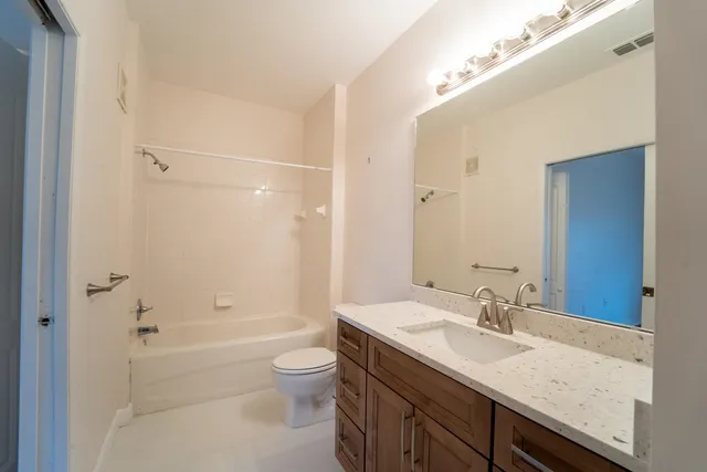 a bathroom with a granite countertop sink a toilet and shower