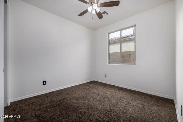 an empty room with a window and a ceiling fan