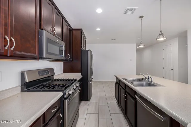 a kitchen with stainless steel appliances granite countertop a sink a stove and a wooden floor