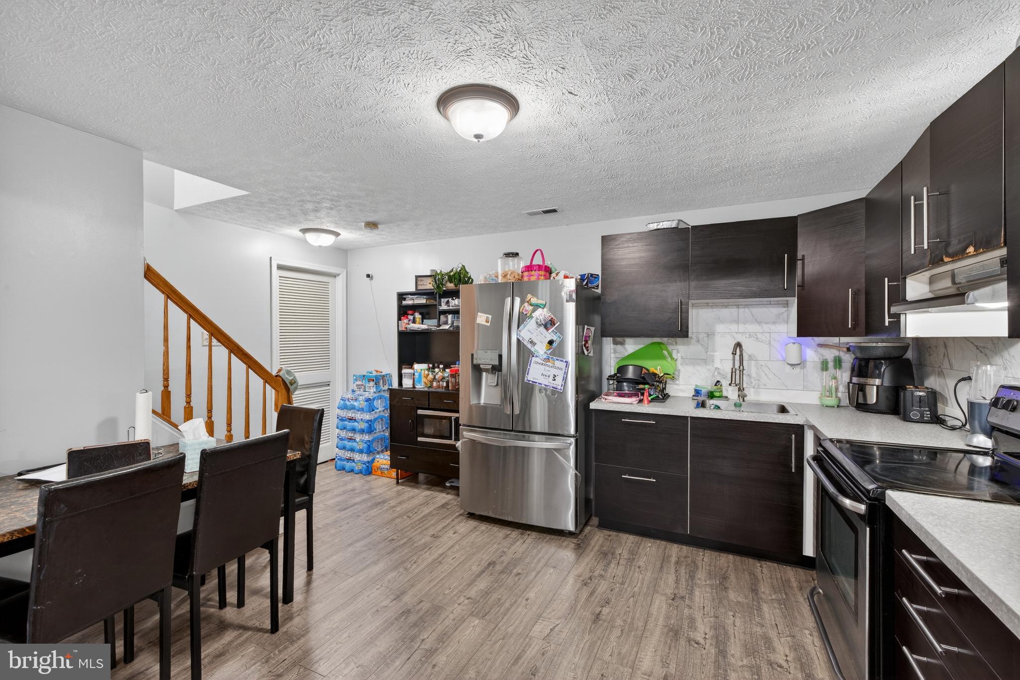 611 Hunting Ridge Drive Frederick, MD 21703 - Photo 44 of 50 a kitchen with stainless steel appliances kitchen island granite countertop a refrigerator a stove a sink dishwasher and a dining table with wooden floor