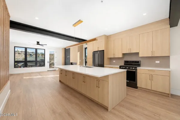 a living room with stainless steel appliances kitchen island granite countertop a refrigerator a sink and a large window