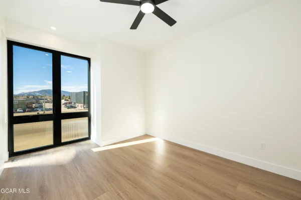 an empty room with wooden floor cabinet and entryway