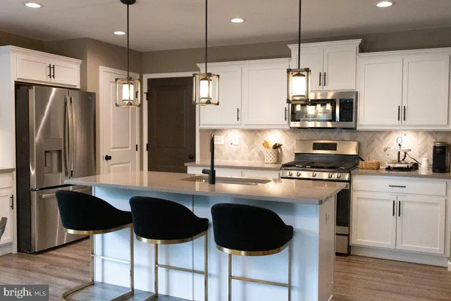 a kitchen with stainless steel appliances granite countertop a sink a stove a refrigerator and island with wooden floor