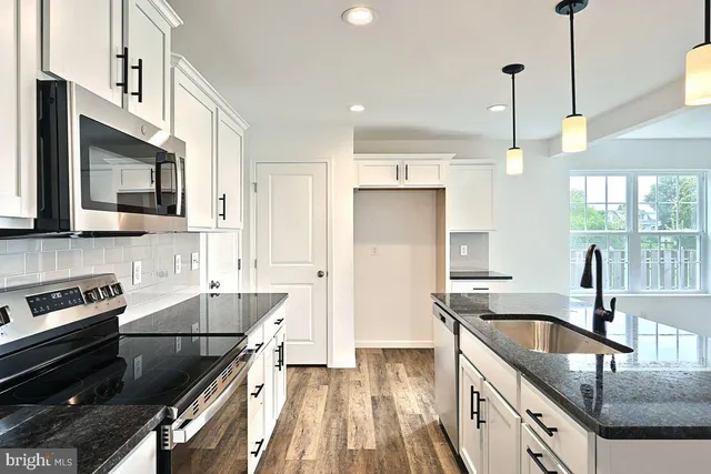 a kitchen with granite countertop a sink a counter space appliances and cabinets