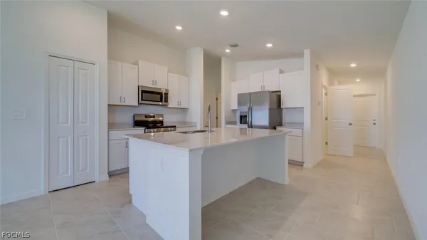 a kitchen with kitchen island a refrigerator and a stove top oven