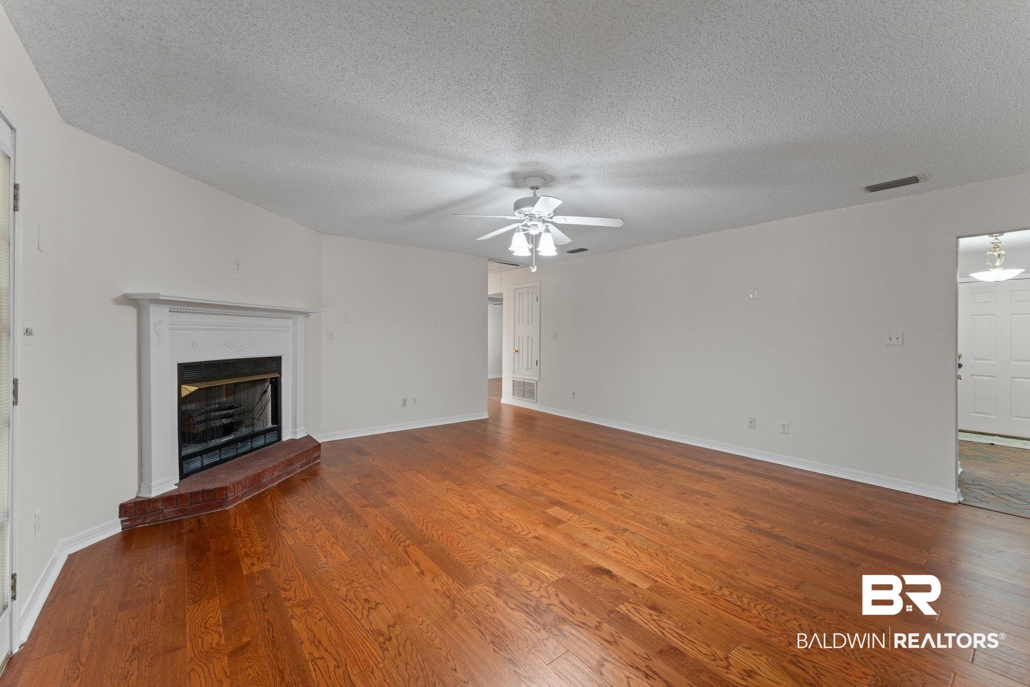 888 Mobile Cut-Off Road St. Stephens, AL 36569 - Photo 20 of 54 Unfurnished living room featuring wood finished floors, a fireplace, a textured ceiling, and ceiling fan