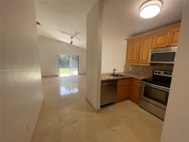 a kitchen with granite countertop a refrigerator and cabinets