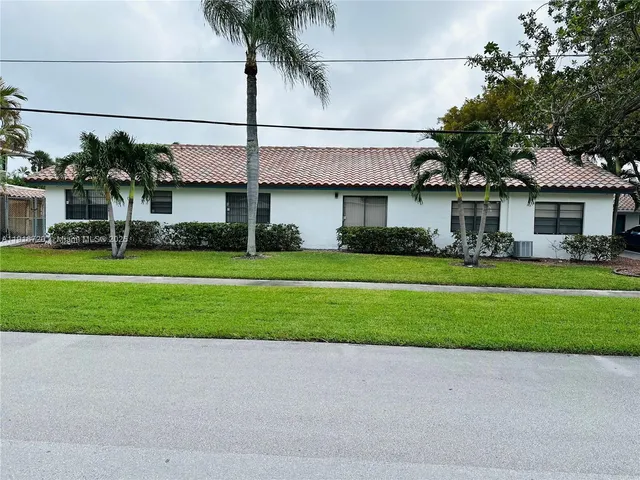 a front view of a house with a garden and palm tree