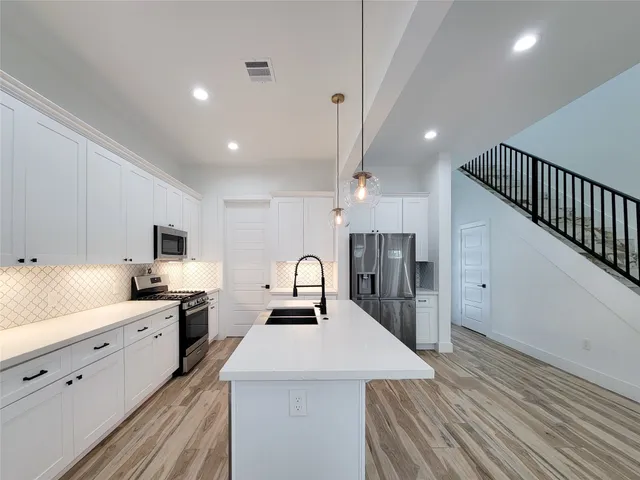 a large kitchen with stainless steel appliances a sink a stove and a refrigerator