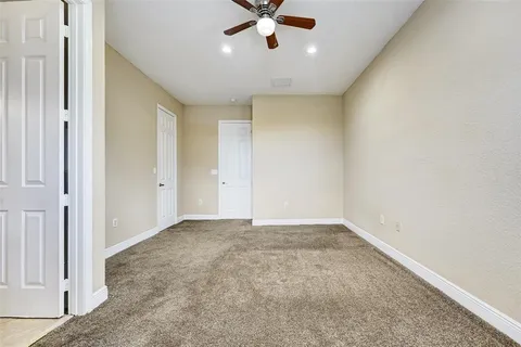 a view of an empty room with a ceiling fan and window