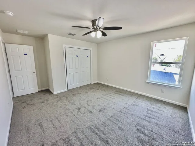 an empty room with a ceiling fan and wooden floor