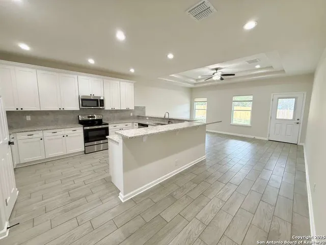 a large white kitchen with lots of counter space wooden cabinets and stainless steel appliances