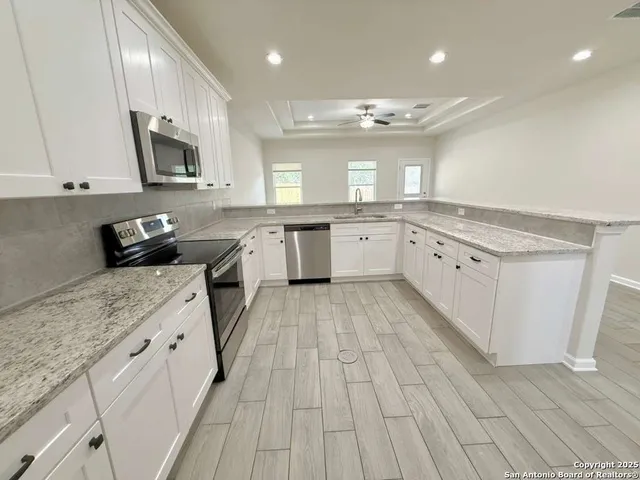 a large kitchen with stainless steel appliances granite countertop a stove a sink and a microwave