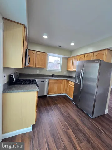 a kitchen with stainless steel appliances granite countertop a refrigerator a sink dishwasher a stove with wooden floors