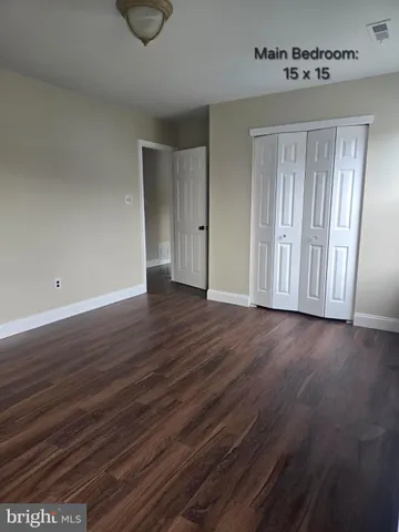a view of an empty room with wooden floor and closet
