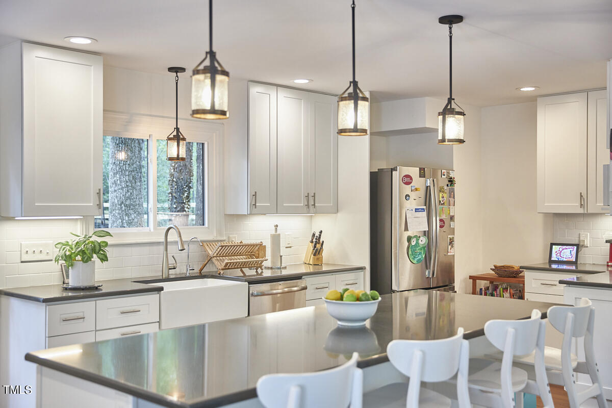 2803 McDowell Road Durham, NC 27705 - Photo 32 of 81 a kitchen with stainless steel appliances granite countertop a sink a refrigerator a stove a dining table and chairs