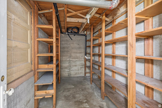 395 North 400 West Logan, UT 84321 - Photo 33 of 48 Basement storage area with extensive built-in wooden shelving, exposed concrete walls, and concrete flooring
