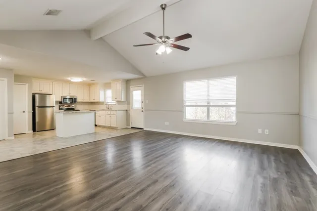 a view of a kitchen with a dishwasher a kitchen island wooden floor and a window