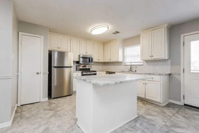 a kitchen with kitchen island a refrigerator sink and cabinets