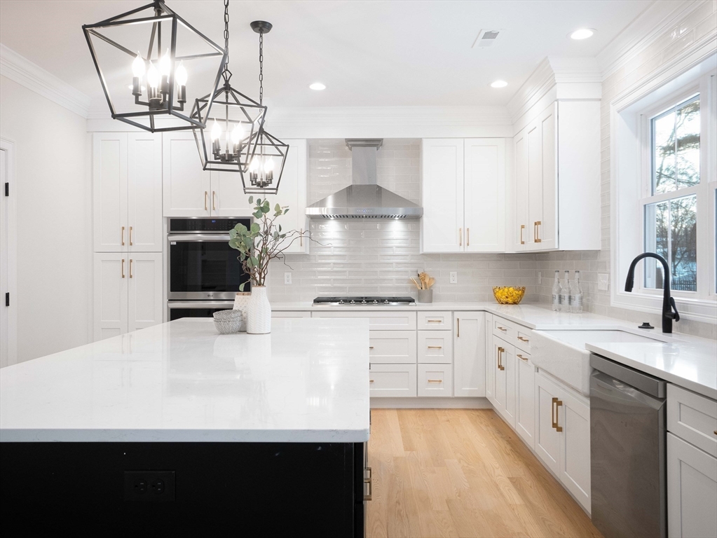 22 Bradford Road Natick, MA 01760 - Photo 3 of 37 a kitchen with kitchen island granite countertop a sink stainless steel appliances and white cabinets
