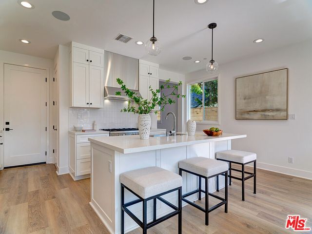 a kitchen with stainless steel appliances a table chairs refrigerator and sink