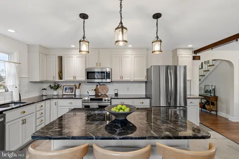 a kitchen with stainless steel appliances granite countertop a sink a refrigerator a stove and white cabinets