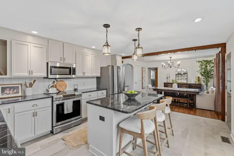 a kitchen with stainless steel appliances granite countertop a stove top oven a sink dishwasher a dining table and chairs with wooden floor
