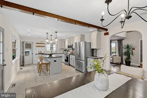 a kitchen with stainless steel appliances kitchen island granite countertop a refrigerator a stove a sink dishwasher and a dining table with wooden floor