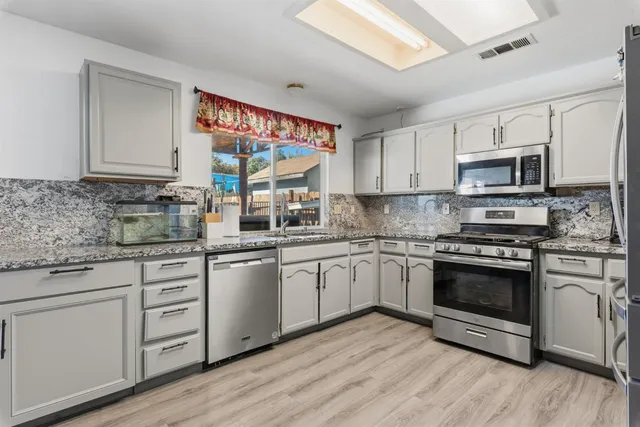 a kitchen with stainless steel appliances granite countertop a stove top oven a sink dishwasher and a refrigerator