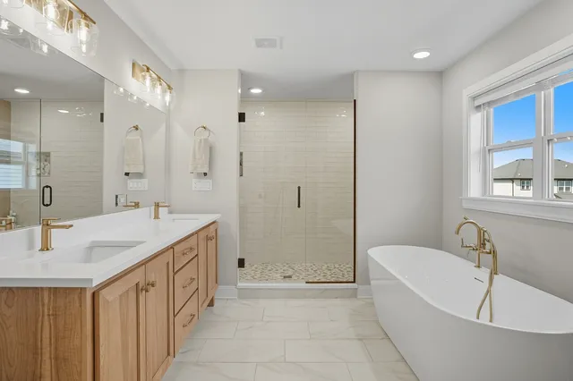 a bathroom with a tub a sink shower and mirror