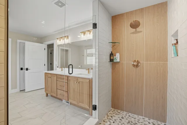 a bathroom with a double vanity sink a mirror and shower