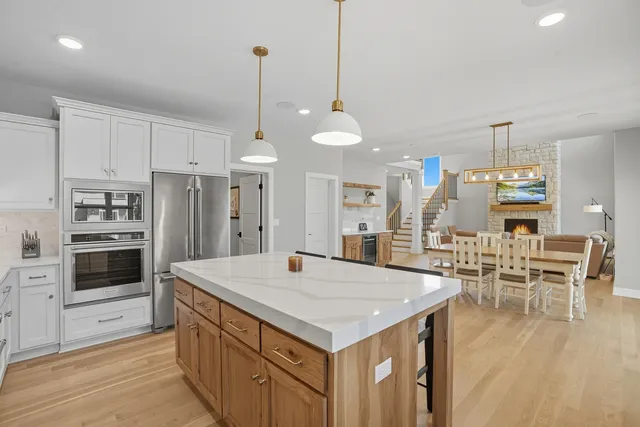 a kitchen with stainless steel appliances kitchen island granite countertop a table chairs stove and white cabinets