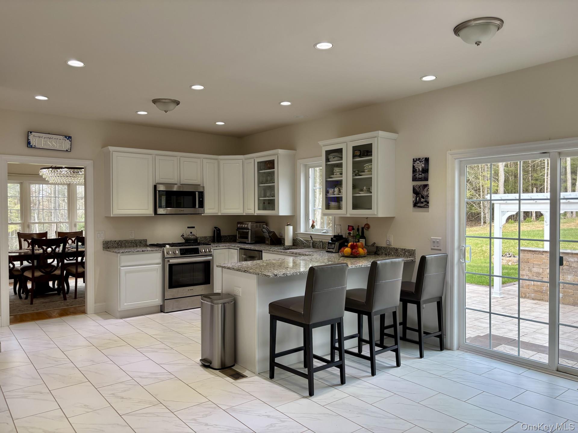 657 Sackett Lake Road Monticello, NY 12701 - Photo 3 of 36 a kitchen with stainless steel appliances granite countertop a stove top oven a sink dishwasher a dining table and chairs with wooden floor