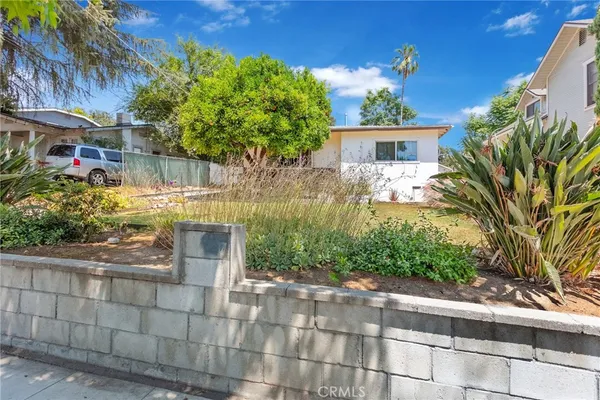 a front view of a house with a yard and potted plants
