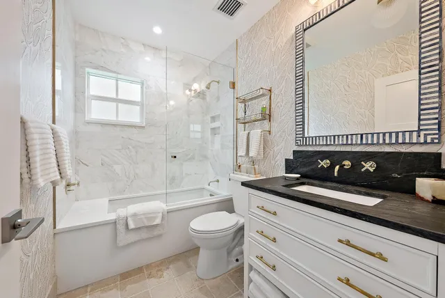 a bathroom with a granite countertop sink a toilet a mirror and shower