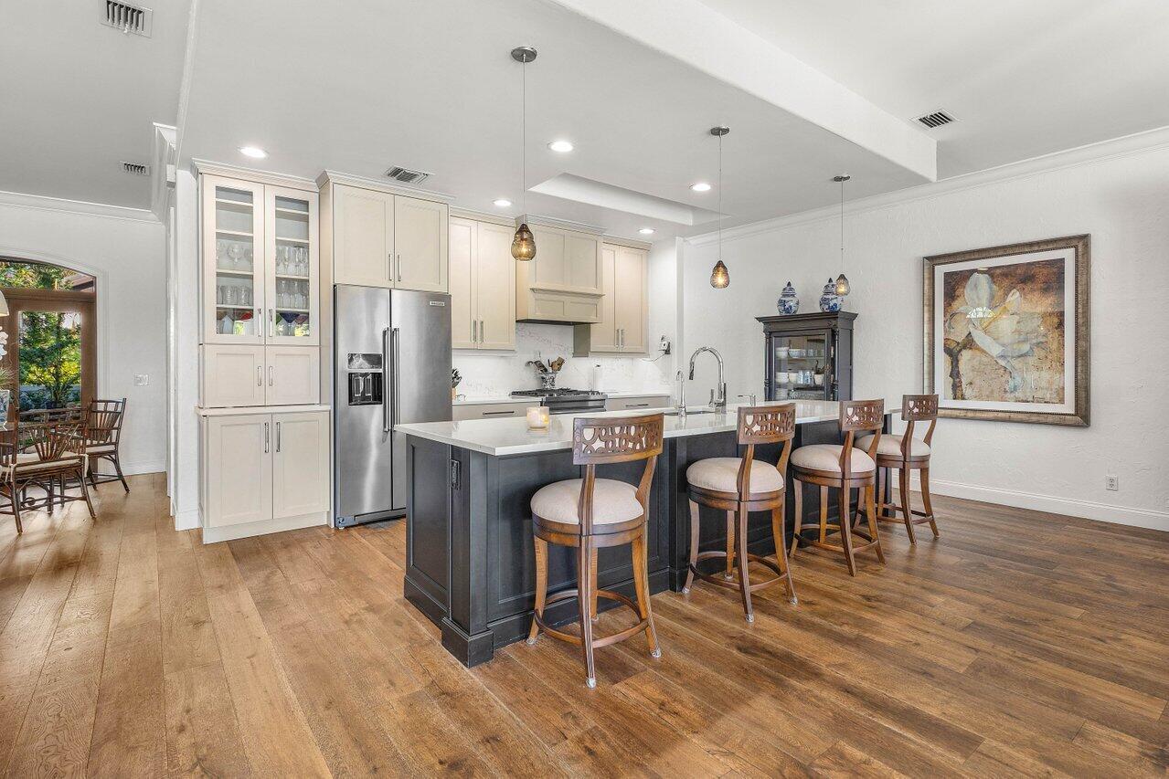 281 Fishermans Way Jupiter, FL 33477 - Photo 16 of 45 a kitchen with stainless steel appliances kitchen island granite countertop a table chairs refrigerator and sink