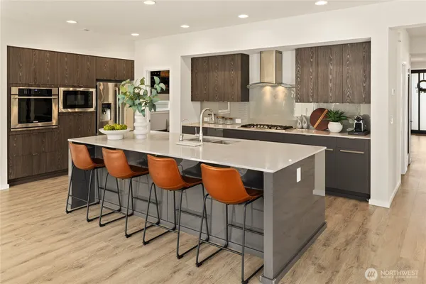 a kitchen with stainless steel appliances granite countertop a stove top oven a refrigerator a sink and chairs