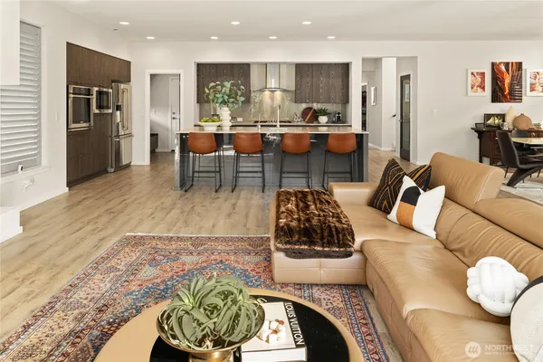 a living room with stainless steel appliances furniture and a wooden floor