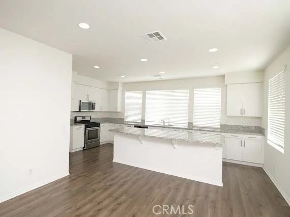 a kitchen with stainless steel appliances granite countertop a stove a sink dishwasher and a refrigerator with wooden floor