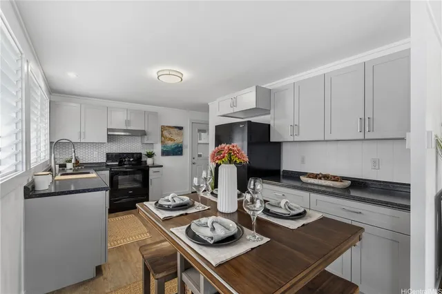 a kitchen with stainless steel appliances granite countertop a stove top oven a sink a dining table and chairs with wooden floor