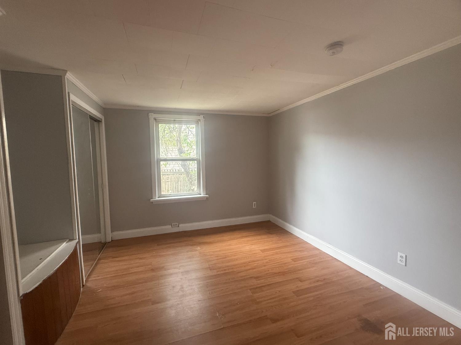 64 Fiat Avenue Iselin, NJ 08830 - Photo 5 of 25 a view of an empty room with wooden floor and a window