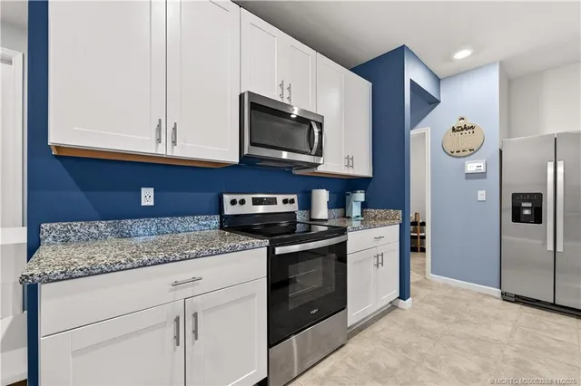 a kitchen with stainless steel appliances granite countertop a sink and a refrigerator